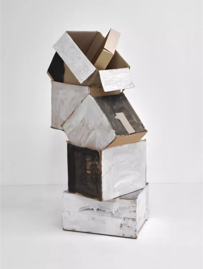 Sculpture de l'artiste autrichien Oswald Oberhuber formée d'un empilement de boites en carton peint en blanc, gris et noir collé sur une caisse bois peinte en blanc et en gris.